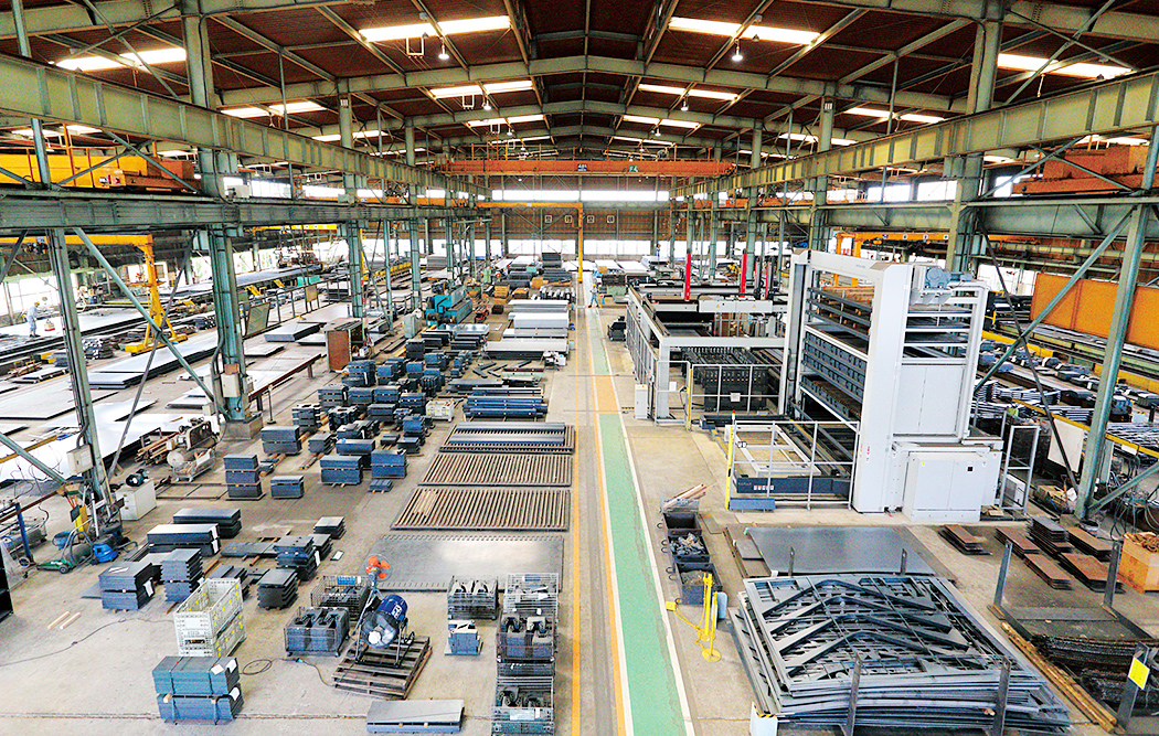 Inside of Yutaka Steel’s Fukuoka Plant, where steel sheets are cut using the GX-F60 fiber laser processing machine. This device and the ASTES4 automatic sorting system are installed on the right of the picture. The products processed using the GX-F60 and ASTES4 can be seen on the left of the picture.
